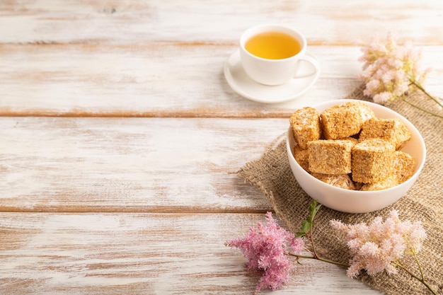 Traditional turkish delight rahat lokum with cup of green tea on a white wooden background side view copy space