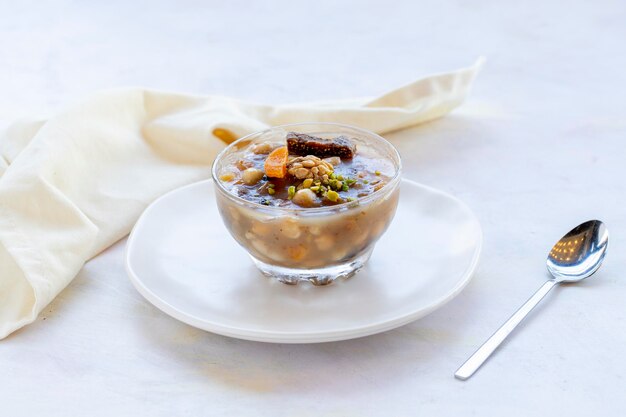 Traditional Turkish Dessert Asure or Noah's Pudding with ingredients on white in stylish bowl Asure quotTurkish Cuisinequot