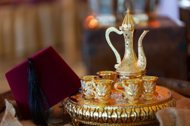 Traditional Turkish Hat Called Fez and Eastern pitcher stand on a tray and Copper glasses