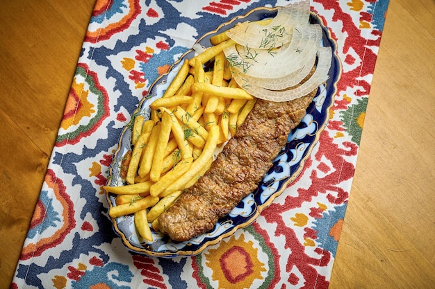 Traditional Turkish lula kebab made of minced meat served on a plate with french fries