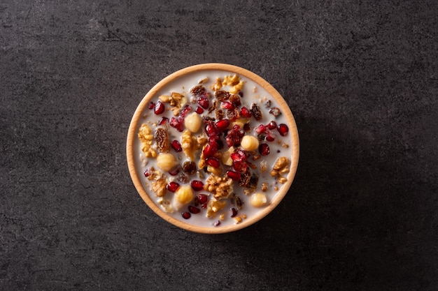 Traditional Turkish Noah's pudding in bowl on black slate background