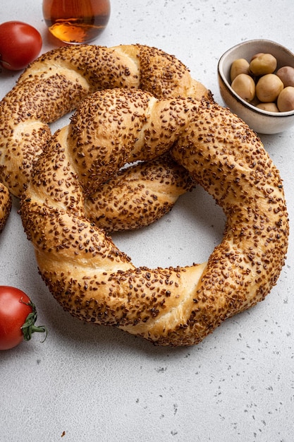 Photo traditional turkish simit bagels with sesame with breakfast ingredients olive and tomato cheese on gray concrete table background