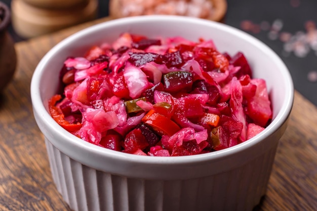 Traditional ukrainian beetroot salad vinaigrette on a white plate on a black concrete or slate background