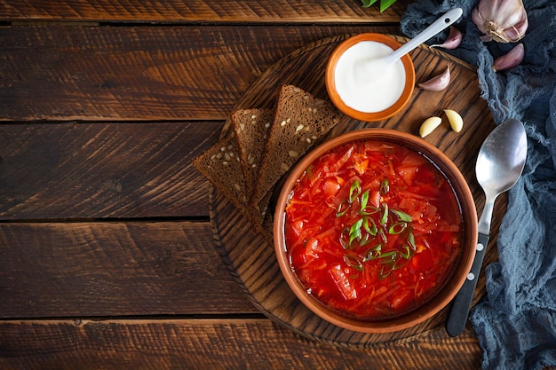 Traditional ukrainian borscht with green onion and sour cream Delicious beet soup in bowl with rye bread Top view