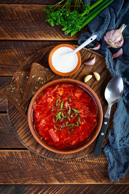 Traditional ukrainian borscht with green onion and sour cream Delicious beet soup in bowl with rye bread Top view