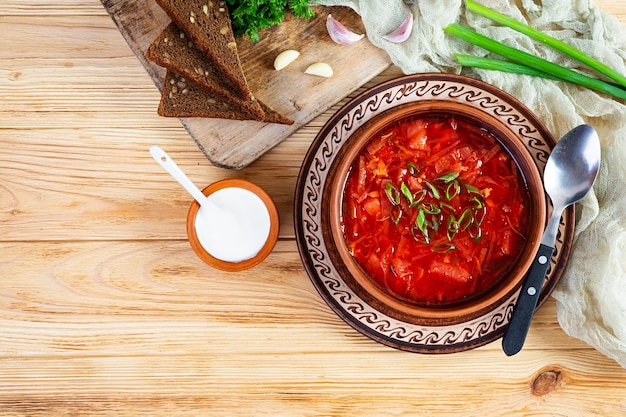 Traditional ukrainian borscht with green onion and sour cream Delicious beet soup in bowl with rye bread Top view