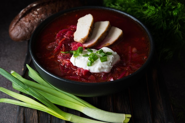 Traditional Ukrainian cuisine - borscht with sour cream and green onions, close up