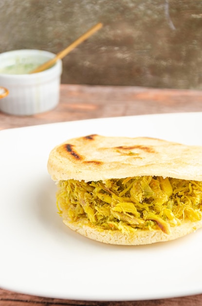 Traditional Venezuelan fish arepa accompanied by guasacas Rustic and wooden background