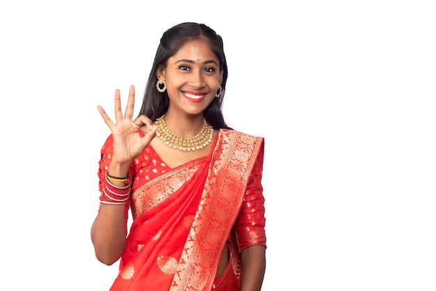 Traditional young smiling girl showing ok sign or thumbs up on a white background