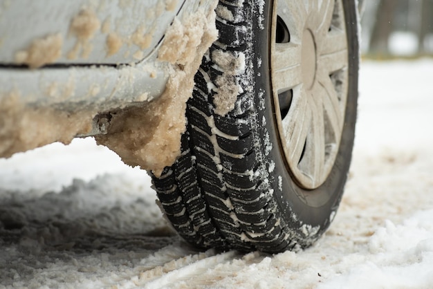 Traffic on winter road after heavy snow Close up of winter tire on the car on snowy road in town