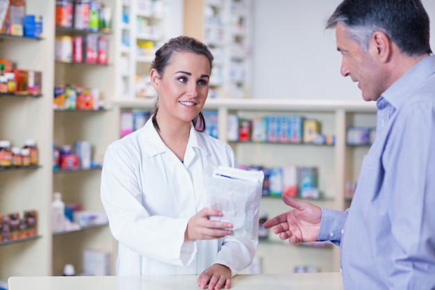 Trainee giving a bag of pills to a customer