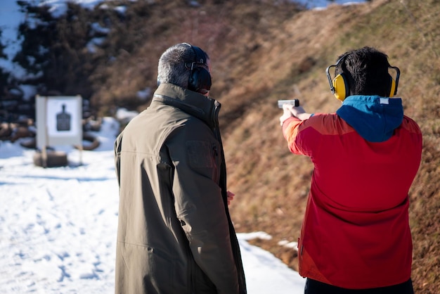 Trainer helping young person to aim with handgun at combat training. High quality photo