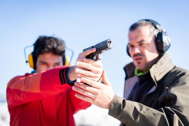 Trainer helping young person to aim with handgun at combat training. High quality photo