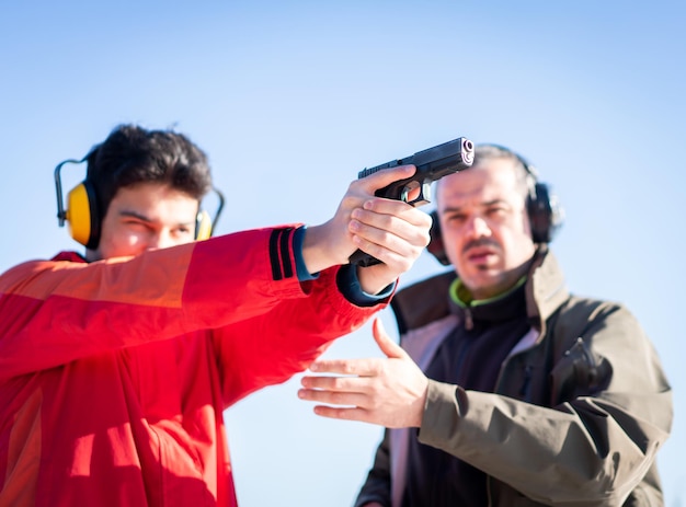 Trainer helping young person to aim with handgun at combat training. High quality photo