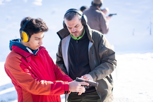 Trainer helping young person to aim with handgun at combat training