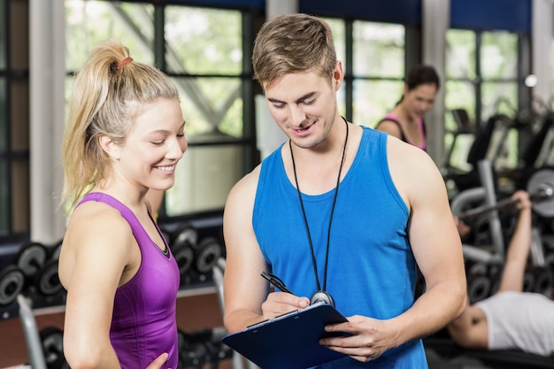 Trainer man talking with sportswoman in gym