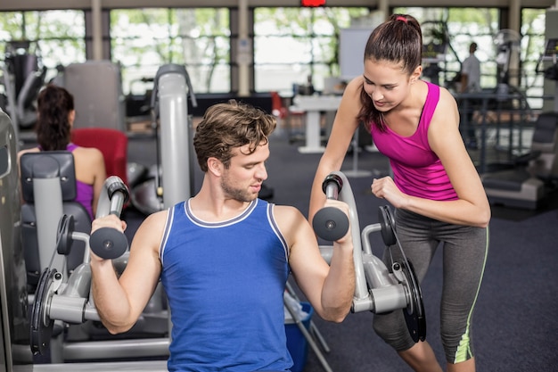 Trainer woman helping athletic man in gym