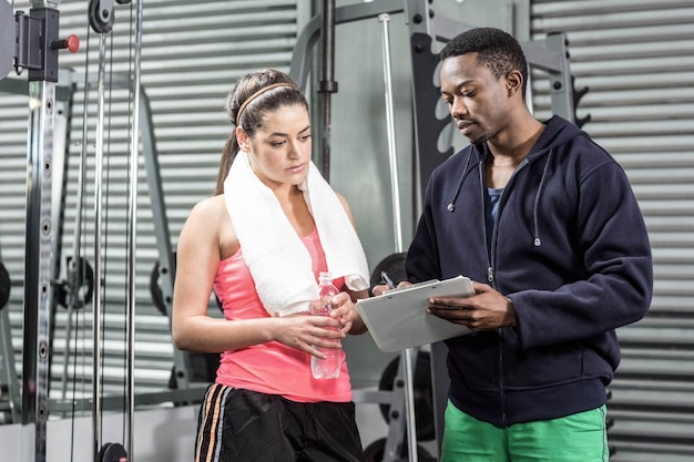 Trainer and woman looking at workout plan at  gym