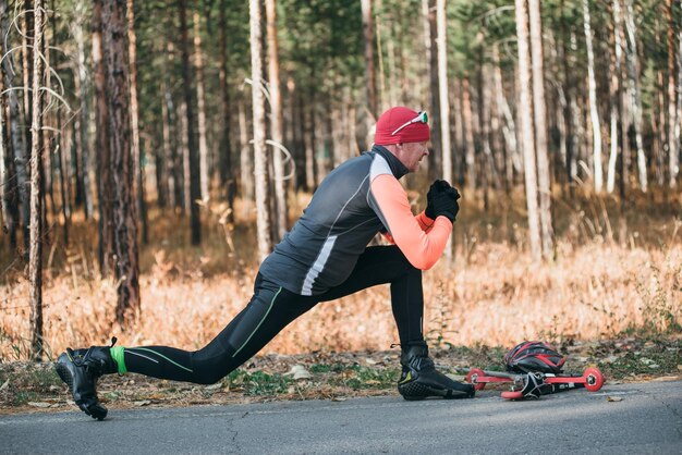 Training an athlete on the roller skaters Biathlon ride on the roller skis with ski poles in the helmet Autumn workout Roller sport The athlete does the workout