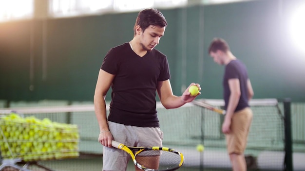 Training on the tennis court young men training a man holding a ball