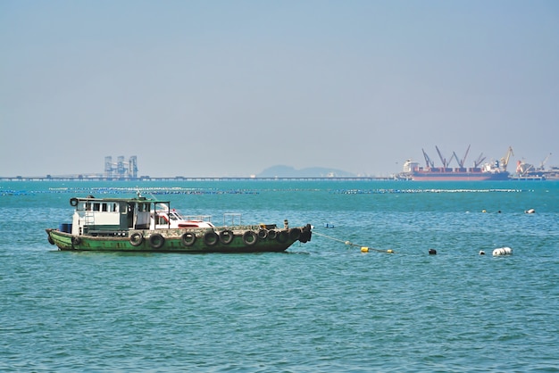 Tranquil Scenery of Fisherman Boat Floating in the Sea with Sea Port in Distant