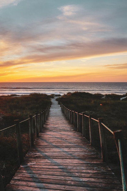 Tranquil scenery of a wooden pathway leadong to the sandy beach at golden sunset