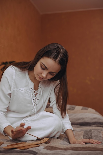 Tranquil woman with aromatic incense stick doing aromatherapy at home