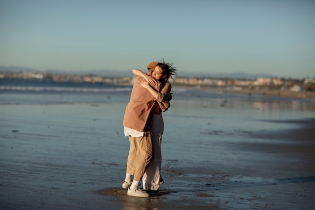 Trans couple hugging on the beach at sunset