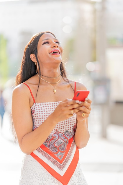 Trans woman laughing and using the mobile outdoors