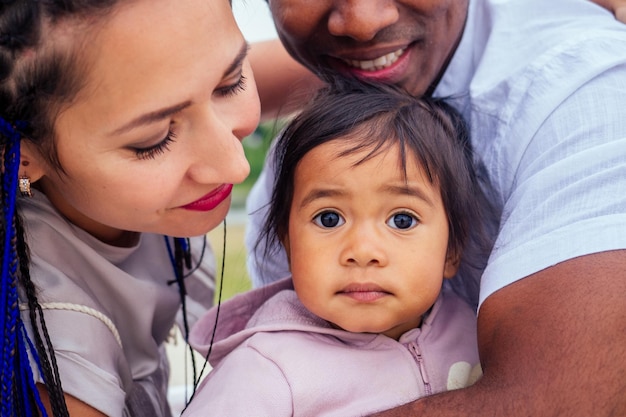 Transnational interracial mother and father walking with their mixed race baby girl in autumn park.