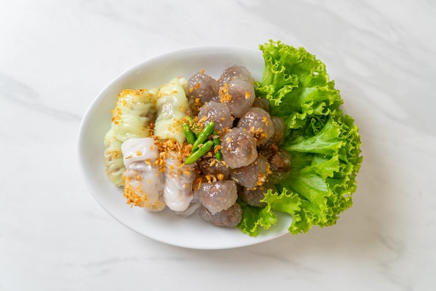 The transparent balls are called Saku Sai Moo or Steamed Tapioca Dumplings Ball with Pork Filling and ( Kow Griep Pag Mor)Pork Steamed Rice Parcels or  Steamed Rice-Skin Dumplings