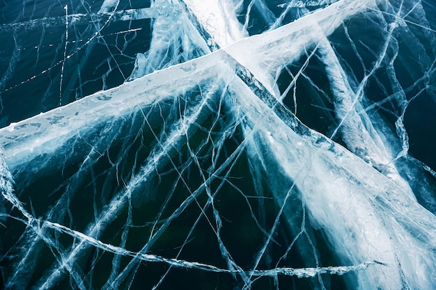 Transparent blue ice with cracks on the lake in winter Baikal Russia