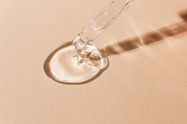 Transparent body serum flowing from a glass pipette front view cosmetic product closeup