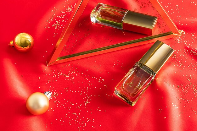 A transparent bottle of perfume lies on a red satin fabric and is reflected in a mirror with Christmas balls the concept of a gift for the holiday