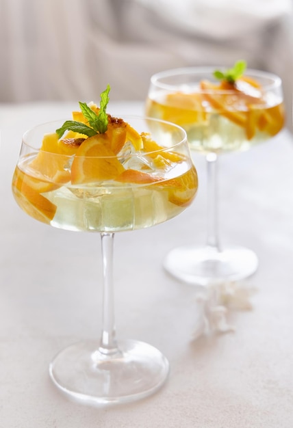 Transparent cocktail with ice cubes in a glass decorated with slices of orange close up