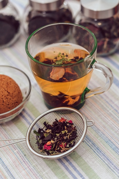 in a transparent Cup of tea on the table, against the background of cans of tea