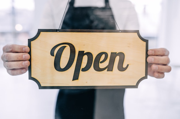 Transparent door with hands holding a closed signboard