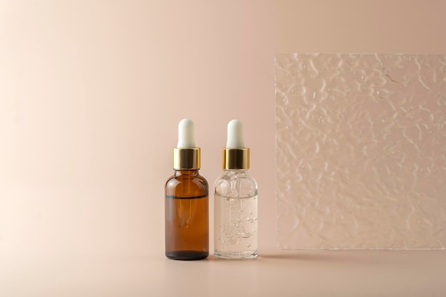 A transparent face serum in dropper bottles or essential oil or gel standing on a beige background