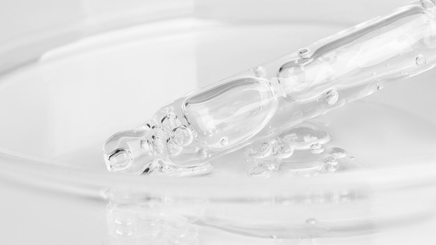 Transparent gel flowing from a pipette into a Petri dish On a white background Closeup