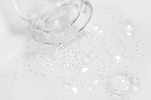 Transparent gel or liquid with bubbles flowing from the bottle onto the background