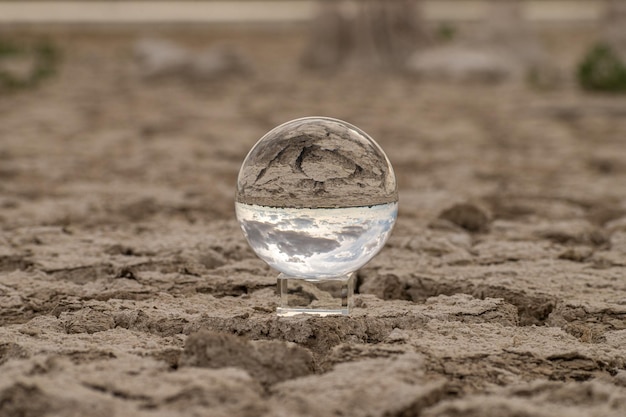 Transparent glass ball dry and cracked land of a lake produced by drought is seen