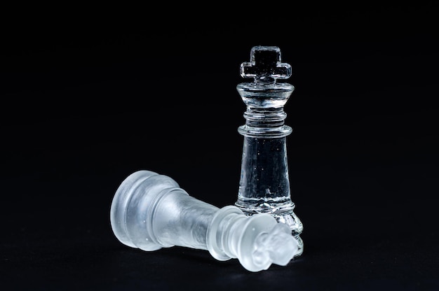 Transparent glass chess on black background selective focus on king piece close up