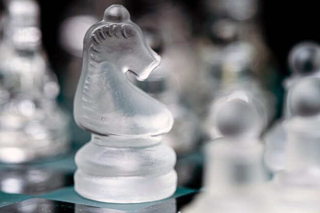 Transparent glass chess on dark background selective focus on horse piece closeup