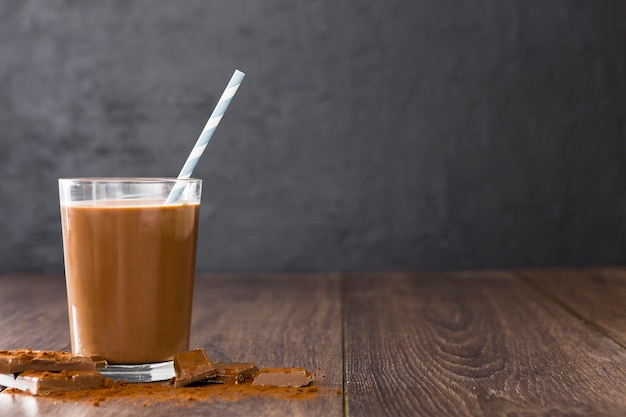 Transparent glass of chocolate milkshake with straw