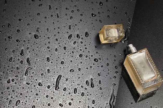 Transparent glass cosmetic perfume bottle on the dark background with water drops