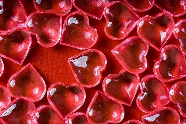 Transparent glass hearts on a red leather background