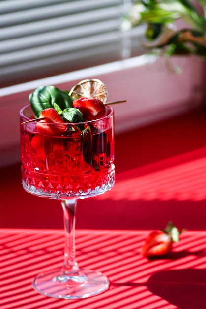 A transparent glass of strawberry cocktail with strawberries on top Red cocktail strawberry mojito