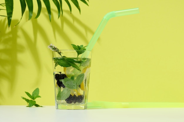 Transparent glass with lemonade mint leaves lemon slices and blackberries in the middle