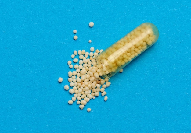 Transparent medical capsules with yellow granules inside on a blue background tablets for treatment vitamins