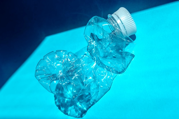 Transparent plastic bottle on a solid blue background for recycle waste Waste separation conceptProtect the environment Garbage processing Preserve nature Selective focus